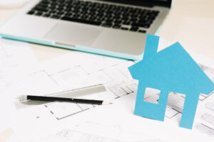 Maison miniature bleue sur des plans de construction, symbole d'un projet immobilier concerné par la loi Le Meur