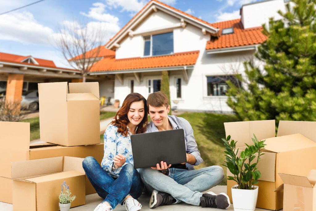 Jeune couple devant une maison neuve entourés de leurs cartons symbole de l'accession à la propriété grâce au PTZ 2026